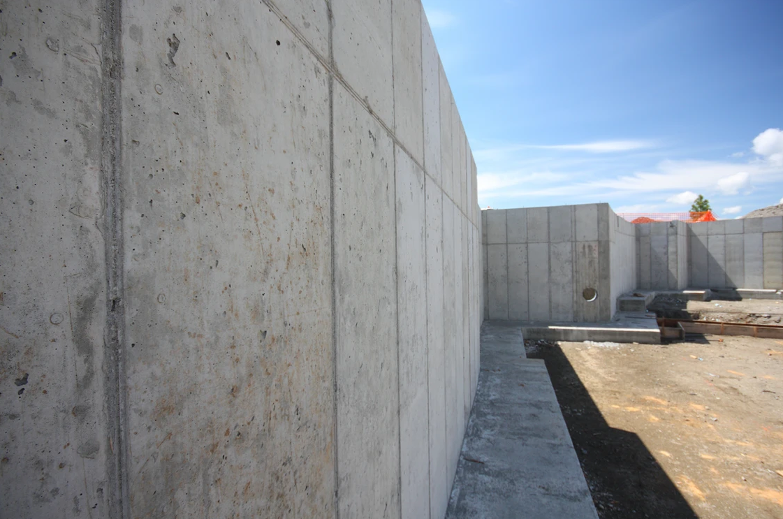 A concrete wall with a cement planter in the foreground