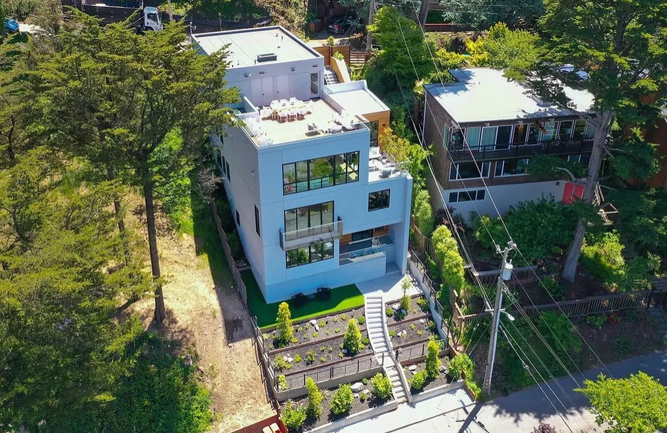 An aerial view of a two story house surrounded by trees